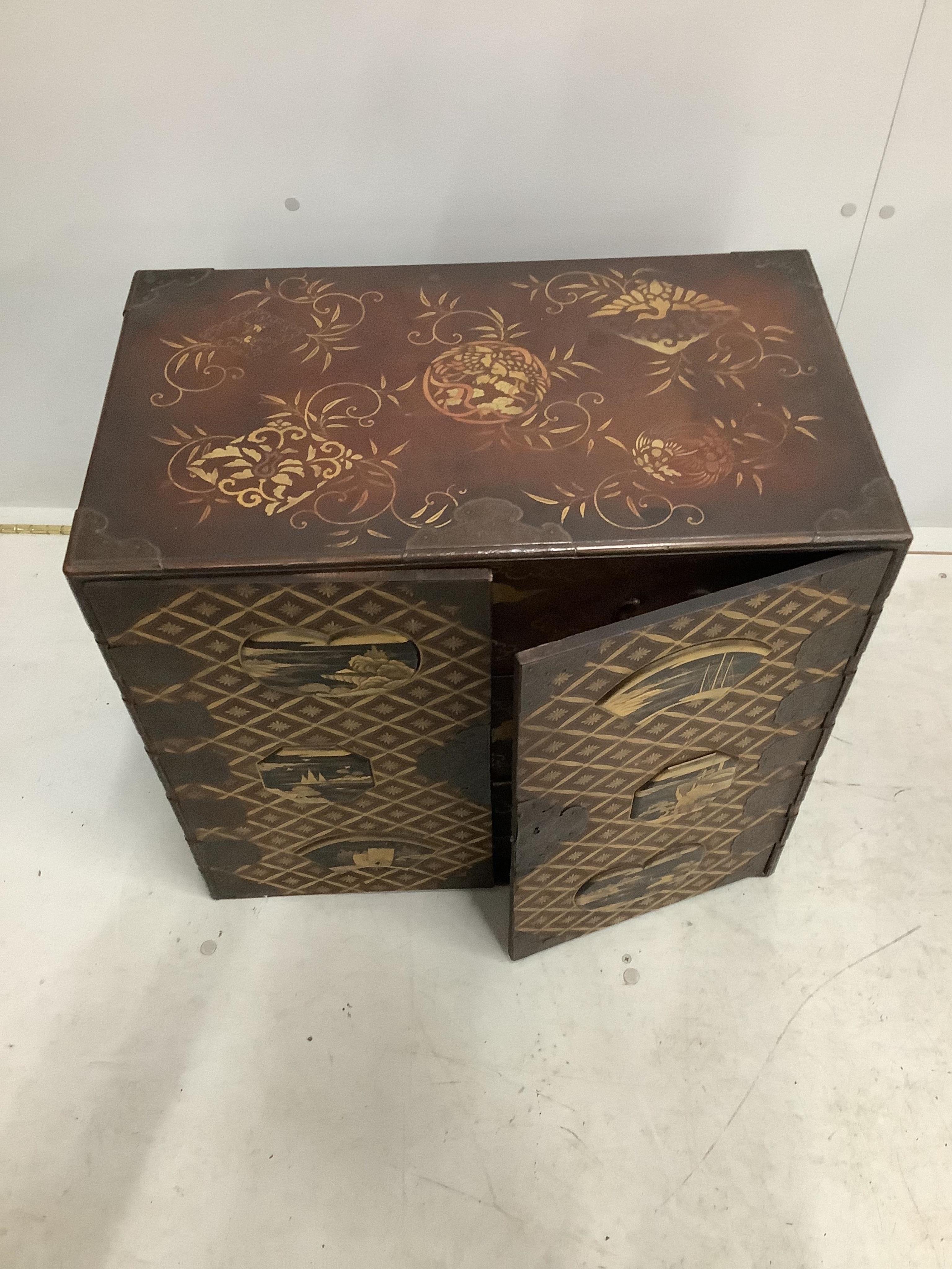 A 19th century Japanese gilt decorated lacquer table cabinet with two doors enclosing three drawers, width 61cm, depth 36cm, height 54cm. Condition - fair to good